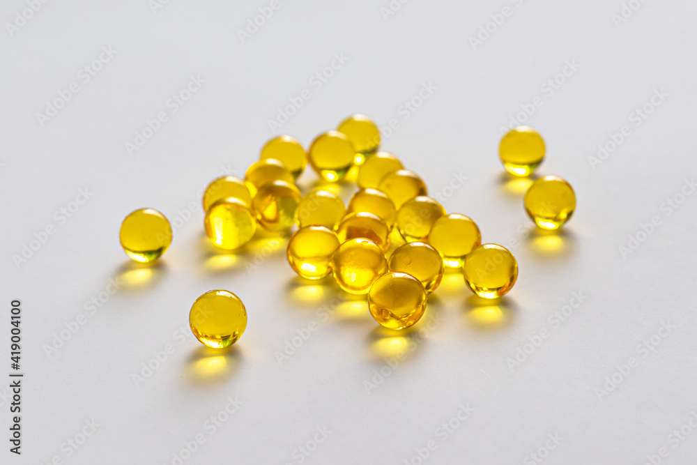 Round yellow capsules with linseed oil on a light background Round yellow capsules with linseed oil on a light background