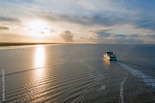Aerial from the ferry from Ameland arriving at Holwerd in the Netherlands at sunset photo