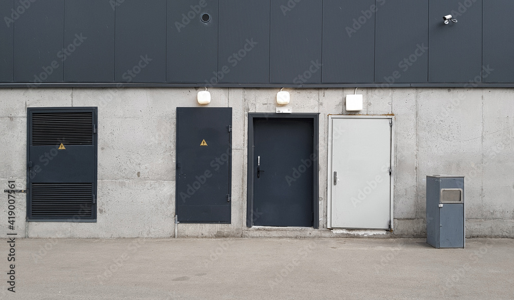 three doors on a concrete wall, technical or fire exit, loading area, building facade