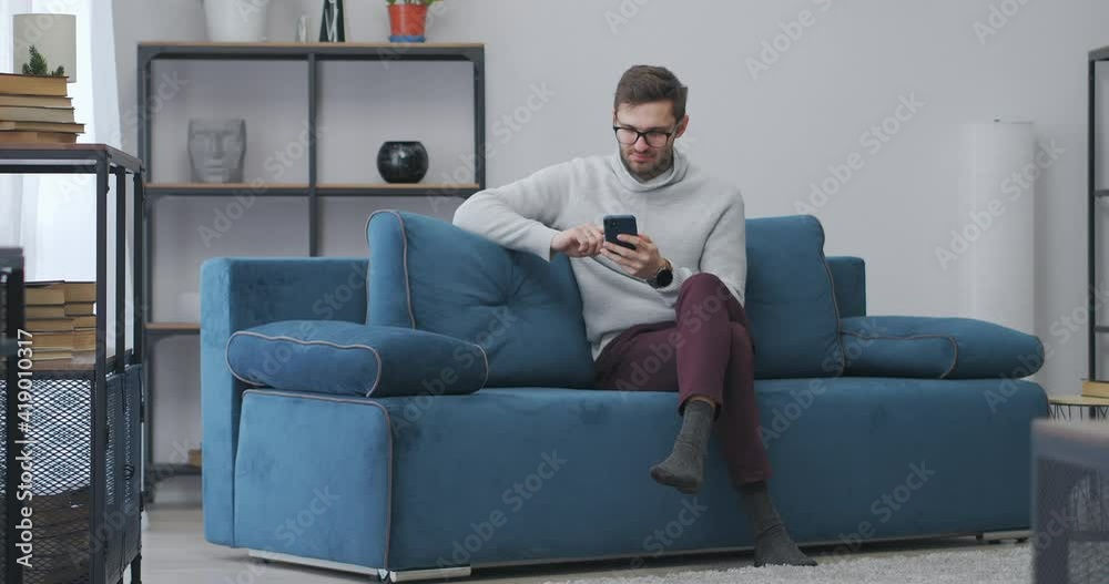 man is playing game in smartphone and winning, rejoicing by win, emotional portrait of adult man in apartment man is playing game in smartphone and winning, rejoicing by win, emotional portrait of adult man in apartment
