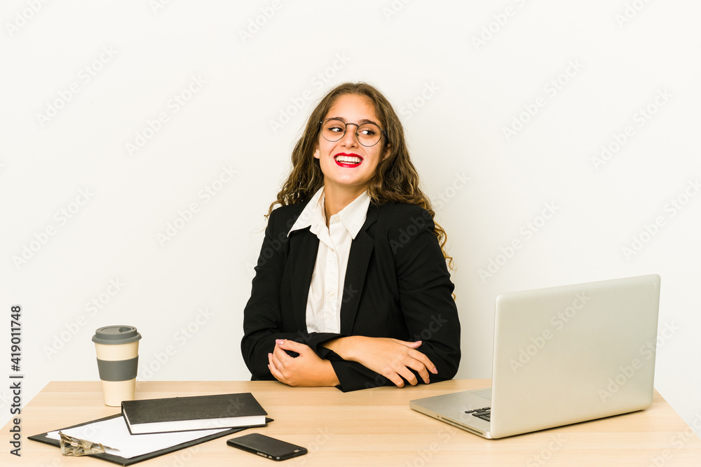 Young caucasian business woman working on her desktop isolated looks aside smiling, cheerful and pleasant. Young caucasian business woman working on her desktop isolated looks aside smiling, cheerful and pleasant.