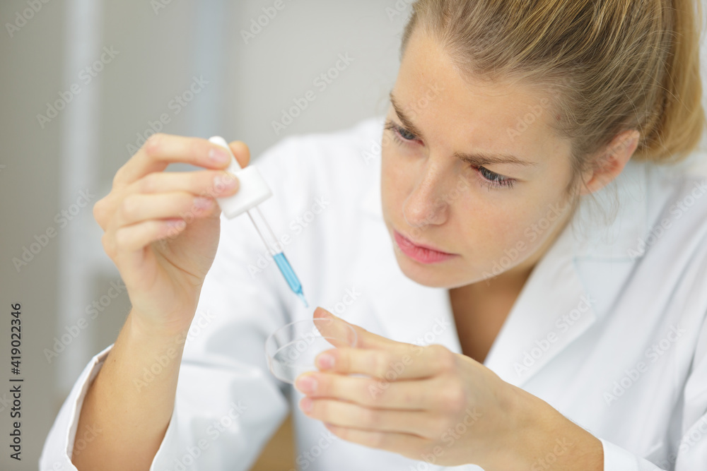 woman scientist adding liquid to test tube with pipette woman scientist adding liquid to test tube with pipette