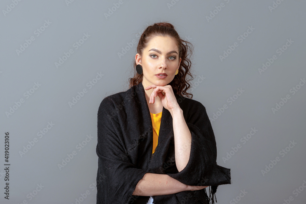 portrait of charming curly-haired woman in a black cloak isolated on a gray background portrait of charming curly-haired woman in a black cloak isolated on a gray background