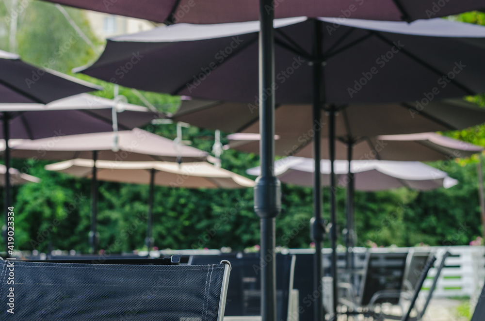 Obraz premium Detail of an outdoor cafe interior with wooden furniture, rotan chairs and purple flowers. Selective focus.