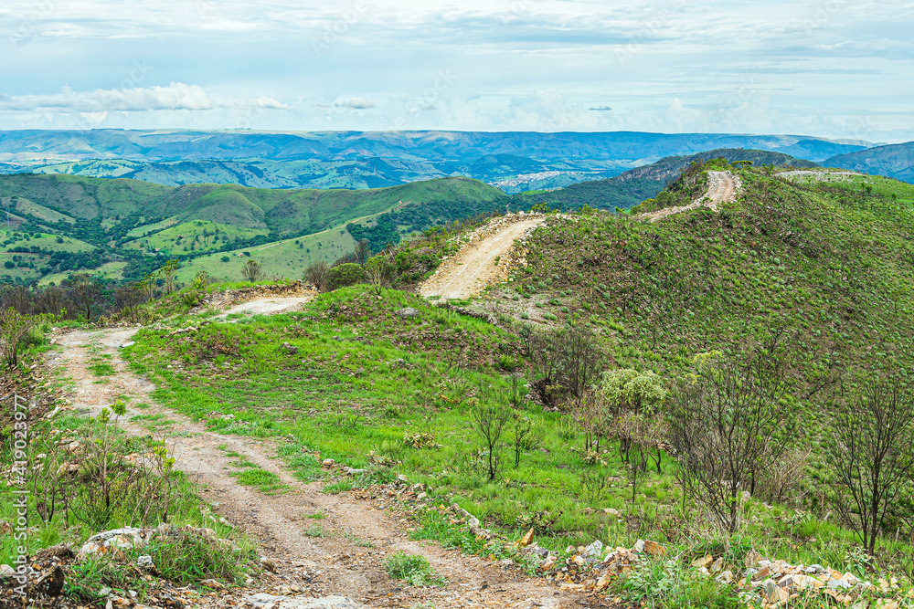Dirt road on top of the hill surrounded by green nature. Landscape of Capitólio MG, Brazil. Minas Gerais state.