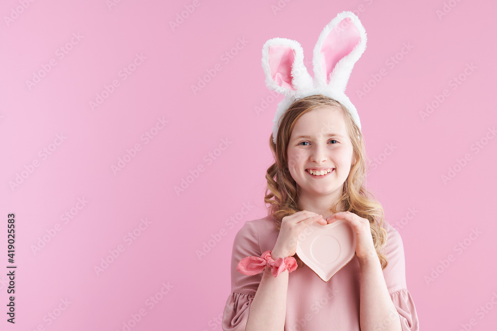 happy stylish child with long wavy blond hair on pink