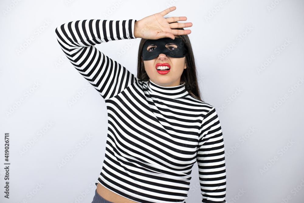 Young beautiful brunette burglar woman wearing mask Touching forehead for illness and fever, flu and cold, virus sick Young beautiful brunette burglar woman wearing mask Touching forehead for illness and fever, flu and cold, virus sick