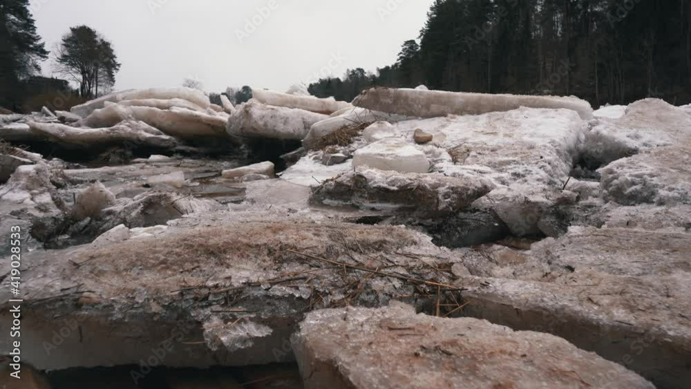 Huge Ice Loads Drift in the River Ogre, Latvia. Stedicam Shot in Snowy Mart Day. Congestion on the River in the Spring. A Large Cluster of Moving Ice Blocks Huge Ice Loads Drift in the River Ogre, Latvia. Stedicam Shot in Snowy Mart Day. Congestion on the River in the Spring. A Large Cluster of Moving Ice Blocks