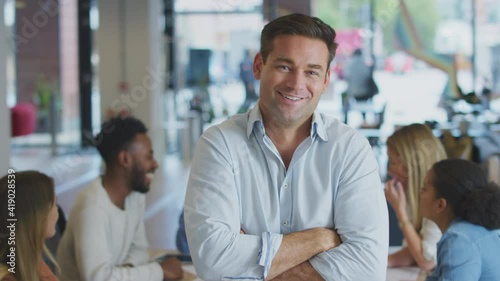 Wallpaper Mural Portrait of confident businessman  with colleagues in background sitting around table having meeting in open plan office - shot in slow motion Torontodigital.ca