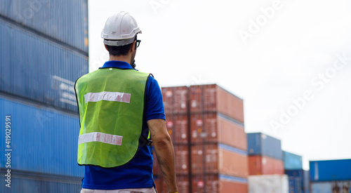 Male logistic staff is wearing safty vest and hardhat while he control the container stage at the harbor. photo