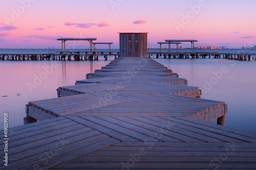 Symmetrical scene of a pier at sunset with purple and pink tones in Mar Menor, Murcia, Spain