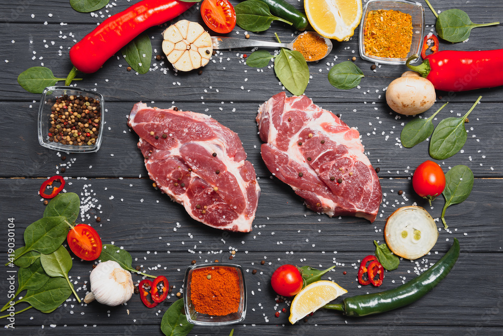 Raw pork meat with spices and vegetables on wooden table Raw pork meat with spices and vegetables on wooden table