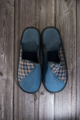 Dos zapatillas de hombre fabricadas con tela de color azul sobre suelo de madera.