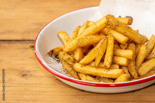 Chips with rosemary, in a shallow bowl on wooden table