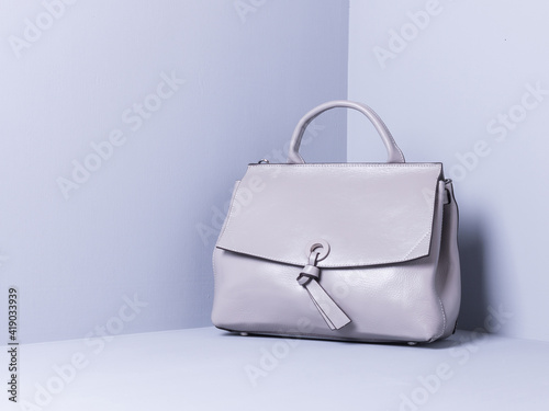 Women's bag of grey color, genuine leather. Grey painted wooden background. Space for text