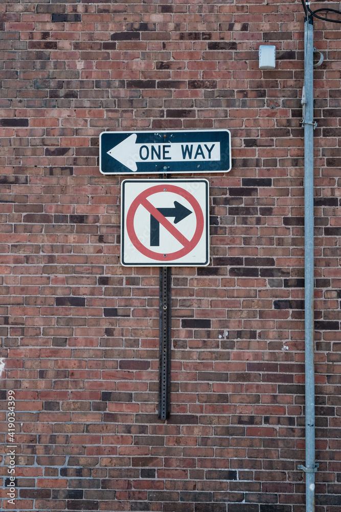 One way and no right turn signs on a brick wall One way and no right turn signs on a brick wall