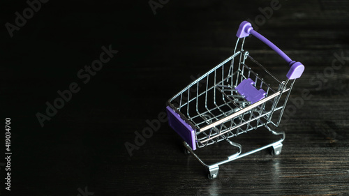 Shopping Cart. Mini shopping trolley on dark wooden background. Mini Shopping Cart On The Table. Business , e-commerce concept