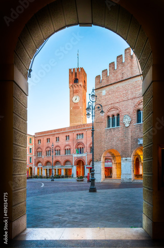 14 february 2021, Treviso, Italy: View of Piazza dei Signori (Lord's Square) through an arch. the background the Palace of the Prefecture and the Civic Tower