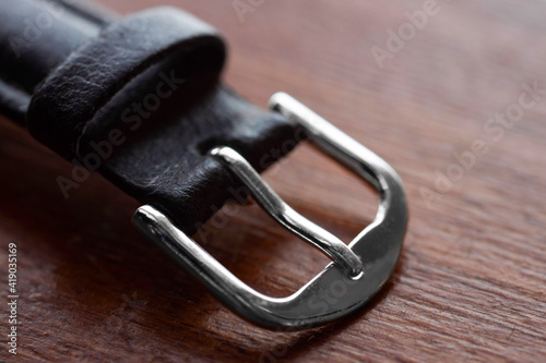 Detail of the buckle of a wristwatch on a wooden background. Macro photography.