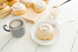 Cinnamon roll on a dessert plate and a coffee cup