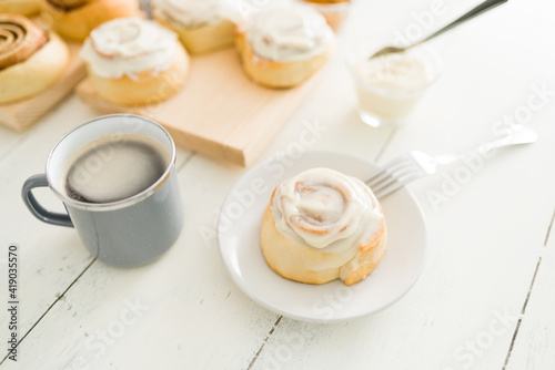 Cinnamon roll on a dessert plate and a coffee cup