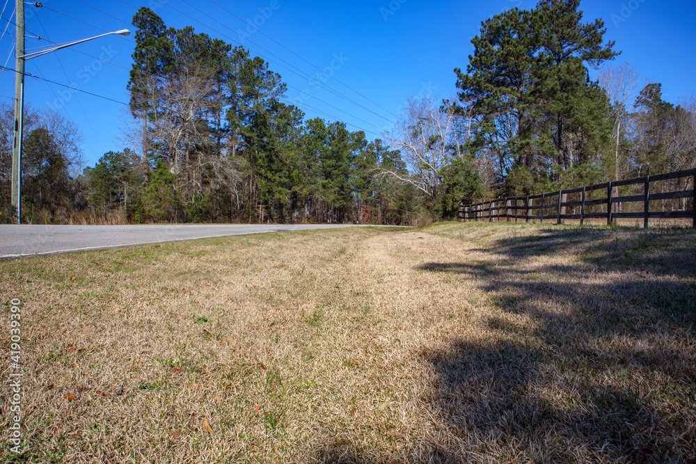Low ground view of a brown wooden fence and a rural road