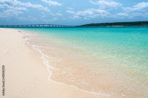 Incredible and transparent emerald green sea with white sands, a bridge in the background that leads to the island of Kurima on a sunny day at Yonaha maehama beach. Miyako Island.