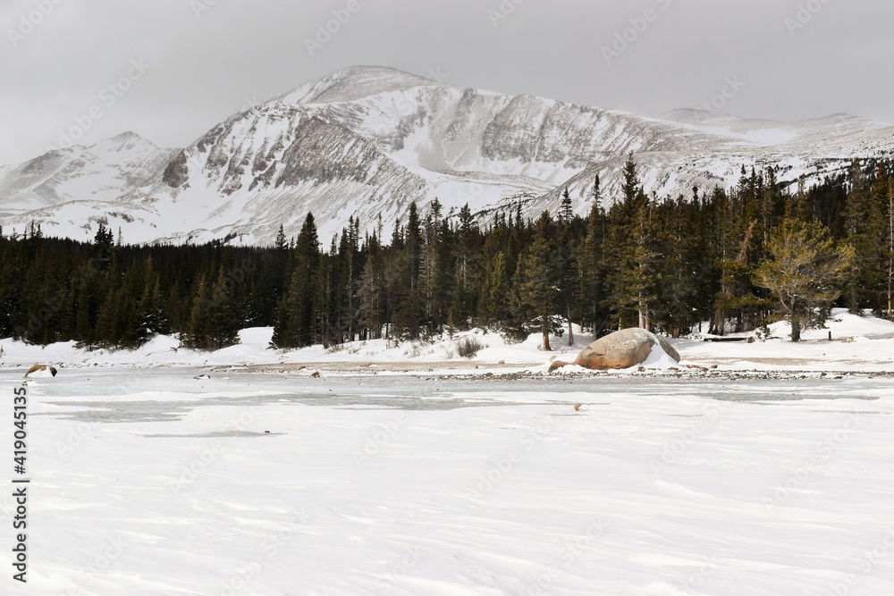 Frozen mountain lake surrounded by snow-capped peaks in the Rockies