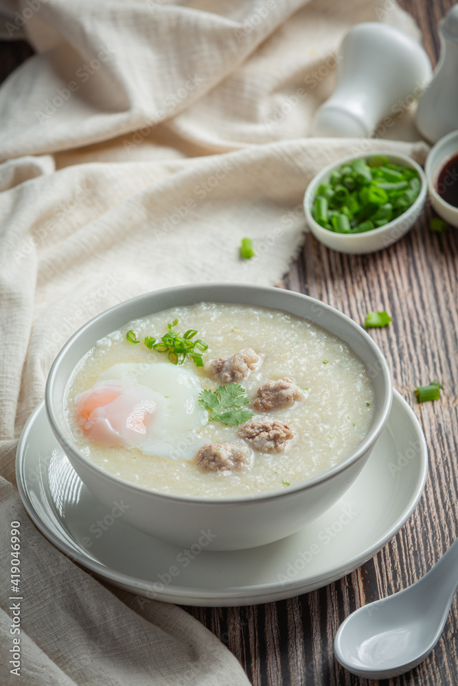 congee with minced pork in bowl on wooden background