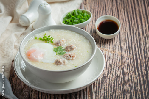 congee with minced pork in bowl on wooden background