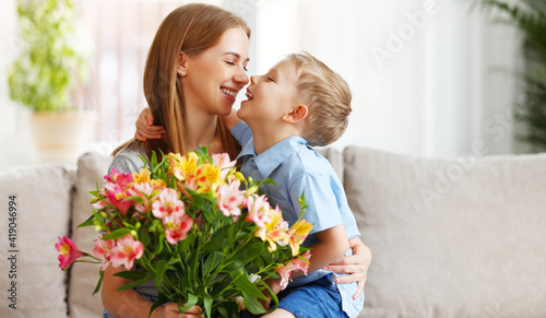 Happy woman and boy with flowers touching nose