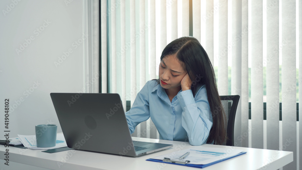 Young asian women are bored at work and feel lazy to deal with data on their laptop in the afternoon. Young asian women are bored at work and feel lazy to deal with data on their laptop in the afternoon.