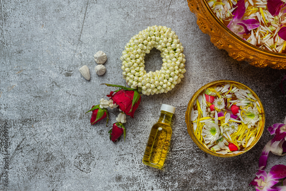 Thai traditional jasmine garland and Colorful flower in water bowls decorating and perfume, marly limestone, plastic water gun on table Thai traditional jasmine garland and Colorful flower in water bowls decorating and perfume, marly limestone, plastic water gun on table