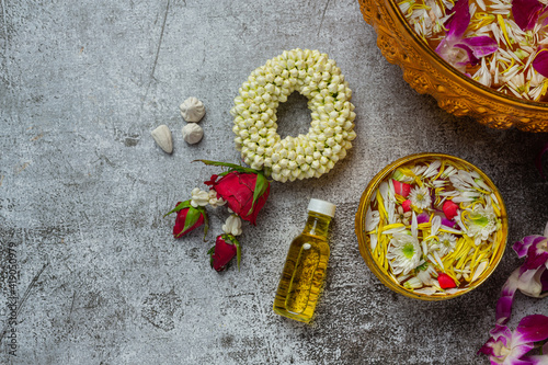 Thai traditional jasmine garland and Colorful flower in water bowls decorating and perfume, marly limestone, plastic water gun on table