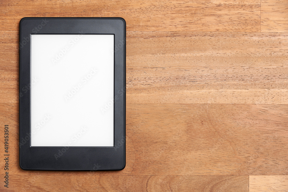 Electronic reader on a wooden surface. Concepts of technology and reading Electronic reader on a wooden surface. Concepts of technology and reading