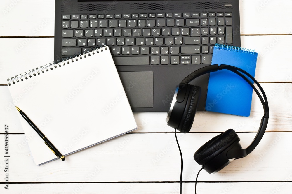 Laptop, notepad,pen with headphones on wooden white table. Workplace. Copy space. Flat lay. Laptop, notepad,pen with headphones on wooden white table. Workplace. Copy space. Flat lay.