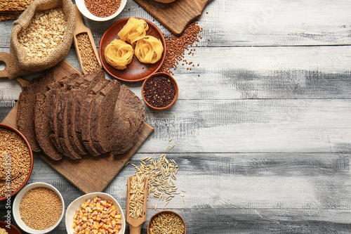 Different cereals, raw pasta and bread on wooden background
