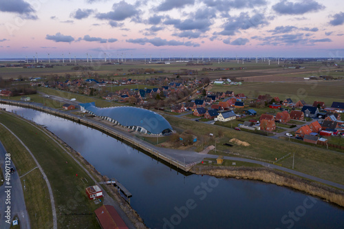 Luftaufnahme von Friedrichskoog Rugenort mit Blick auf den Ort und das Rugenorter Loch im Abendlicht, Schleswig Holstein, Deutschland