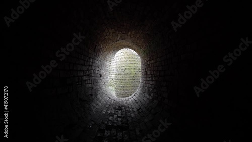 Old abandoned oval brick tunnel  of the 19th century in the day. Dollying-in view.