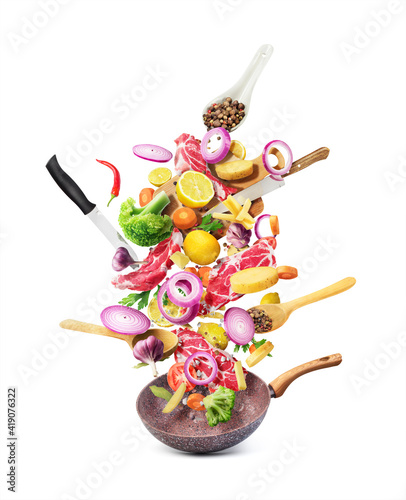 Cooking concept. Vegetables and meat are flying out of the pan isolated on white background. photo