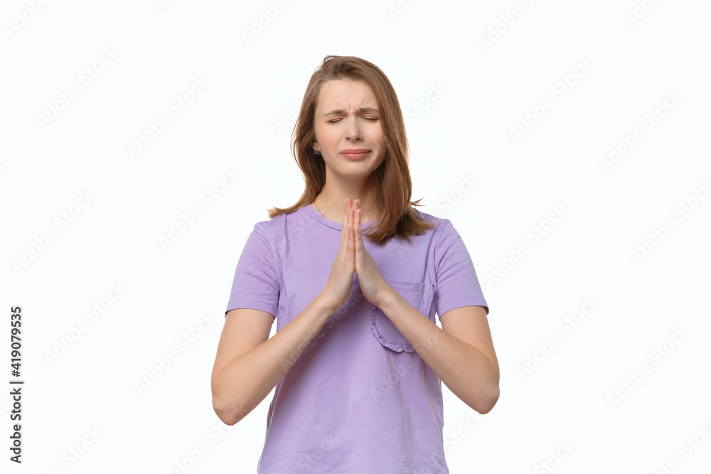 Attractive girl looks with imploring expression asks to give one more chance, keeps palms pressed together Attractive girl looks with imploring expression asks to give one more chance, keeps palms pressed together