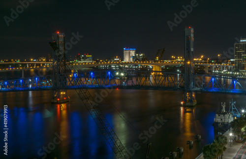 main street bridge (John T. Alsop Jr.) in Jacksonville, Florida bathed in blue neon lights after dark. St. Johns river passes underneath.