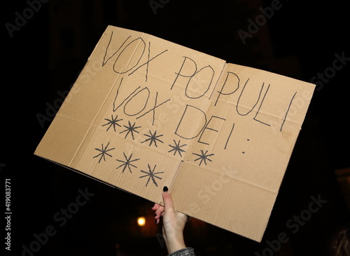 Female hand holding a note on a banner VOX POPULI VOX DEI and 8 sybolic stars close up photo