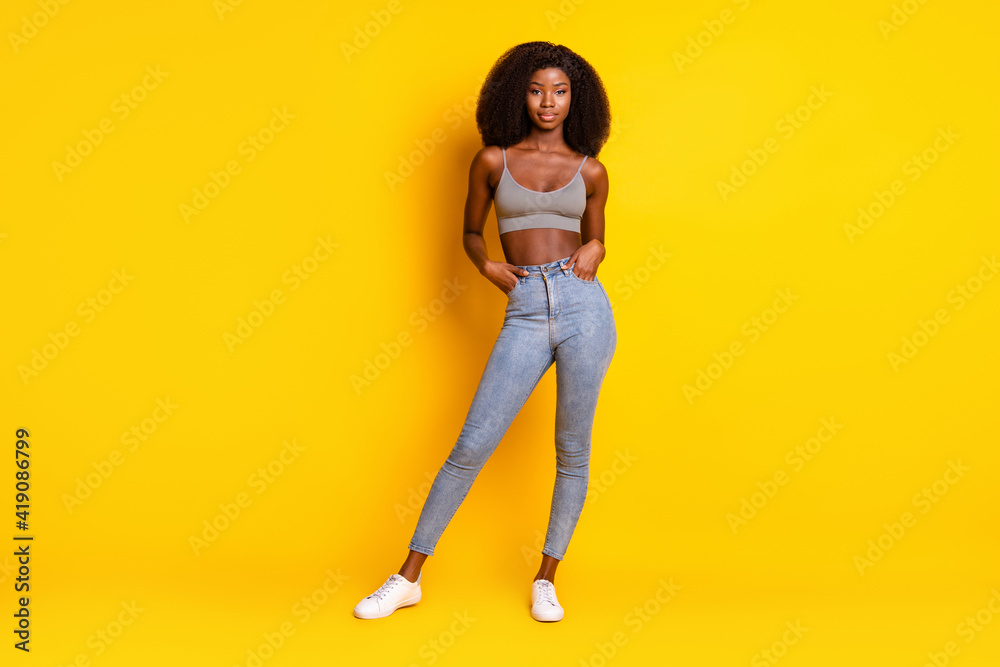 Photo of charming confident lady hands pockets wear cropped singlet jeans footwear isolated yellow color background Photo of charming confident lady hands pockets wear cropped singlet jeans footwear isolated yellow color background