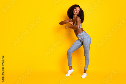 Photo of lady festal dance look empty space wear grey cropped top jeans shoes isolated yellow color background © deagreez