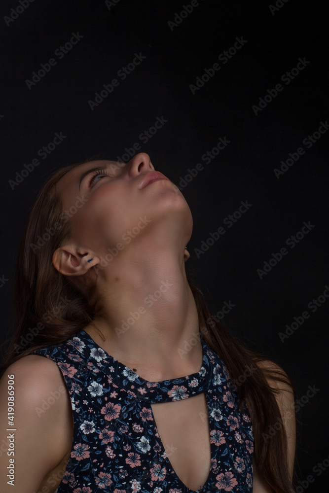 Obraz premium brown-haired woman with long hair, in a blue dress with flowers, on a black background