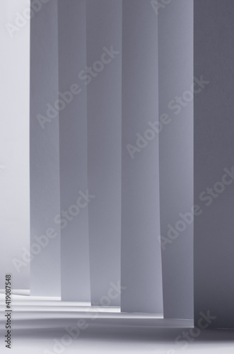 Abstract white grey background with contrast perspective of stripes, light and shadow as pattern, vertical.