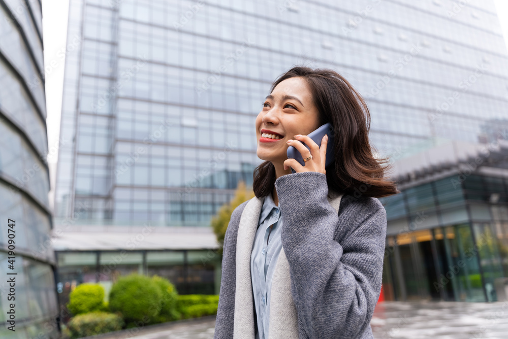 happy young asian business woman talking on the mobile phone walking in the office building happy young asian business woman talking on the mobile phone walking in the office building
