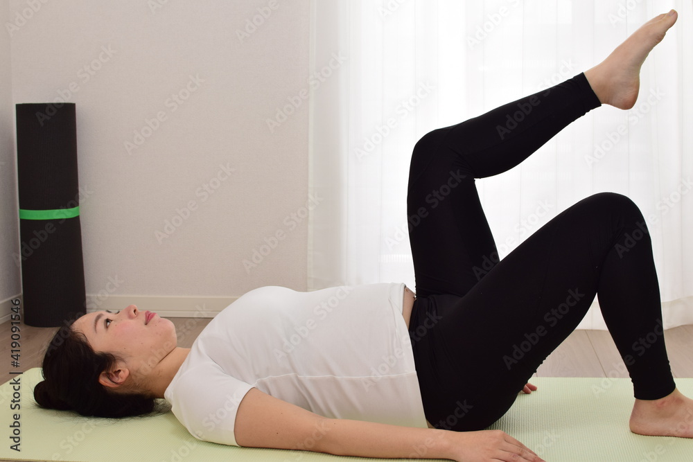 Obraz premium A young pregnant woman is doing fitness at home. .It is important to exercise during pregnancy.