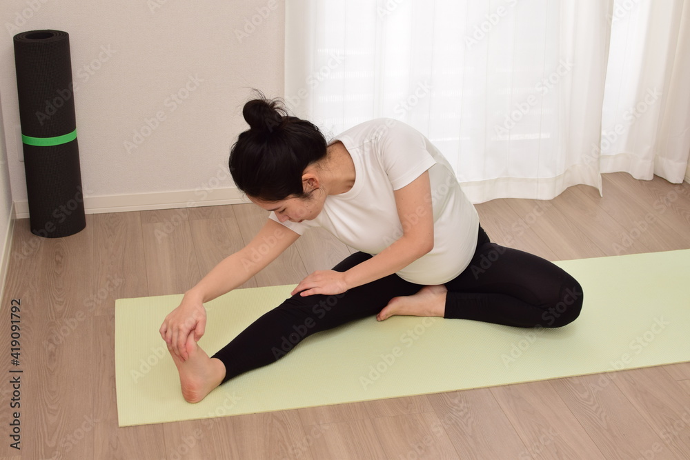 A young pregnant woman is doing fitness at home. It is important to exercise during pregnancy. A young pregnant woman is doing fitness at home. It is important to exercise during pregnancy.